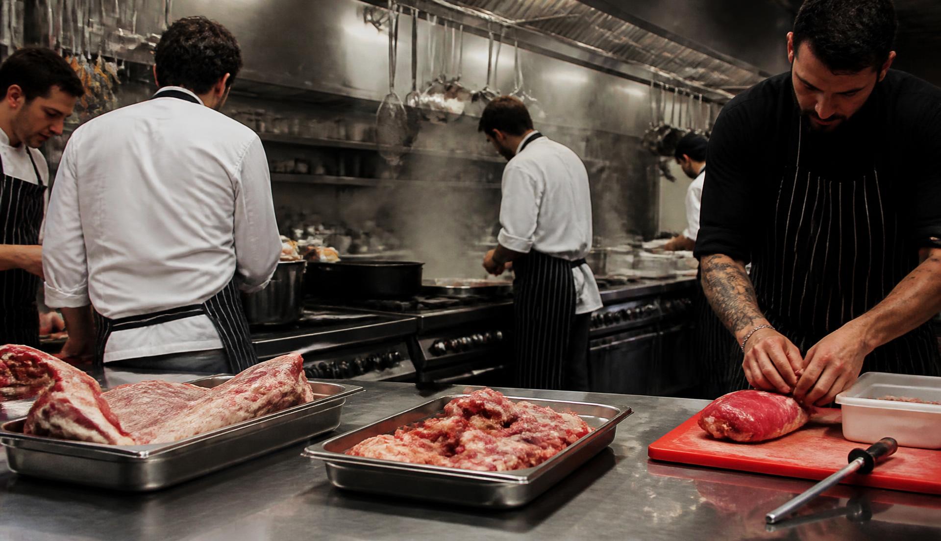 Equipa de cozinha profissional a trabalhar com carne fresca